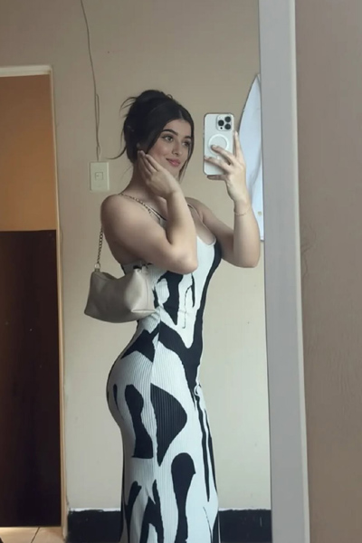 Confident woman posing near a wall in a modern patterned outfit.
