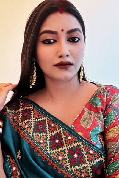 Portrait of a woman in Indian attire with gold accessories and bold makeup.