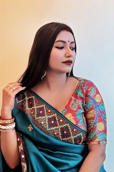 Elegant woman wearing ethnic saree with jewelry and calm expression.