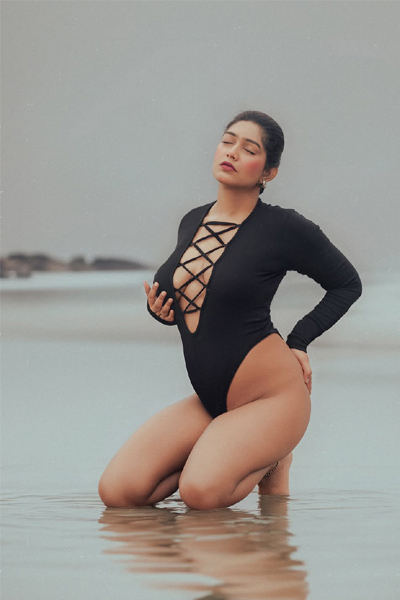 Confident woman posing near the shoreline on a cloudy day.