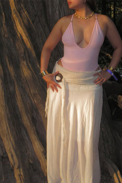 Stylish woman standing near a forest area with calm expression.