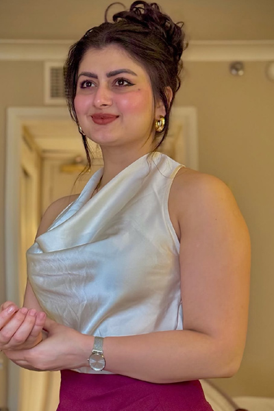 Young woman in chic maroon skirt and white blouse taking mirror selfie in hotel room