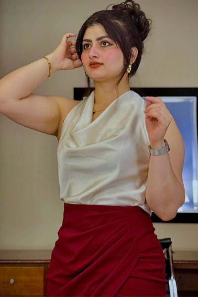 Fashion model posing indoors in modern outfit with white top and maroon skirt